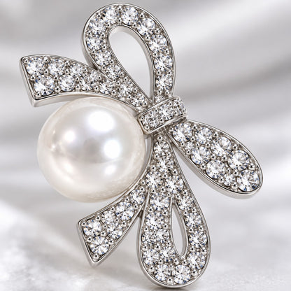 Macro view of the crystal-paved silver ribbon bow and faux pearl on a drop earring