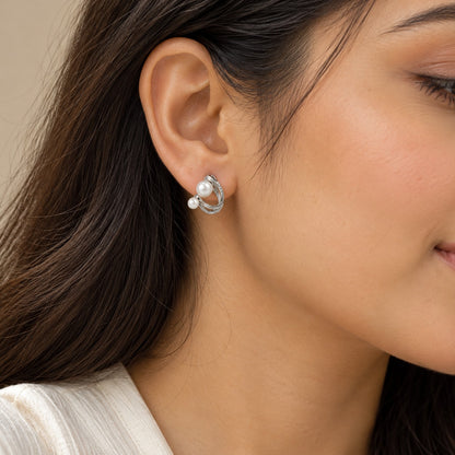 Woman wearing silver double pearl twisted hoop stud earrings, close-up of ear and jawline