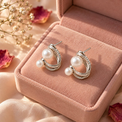 Silver double pearl twisted hoop stud earrings on a blush-pink velvet jewellery box