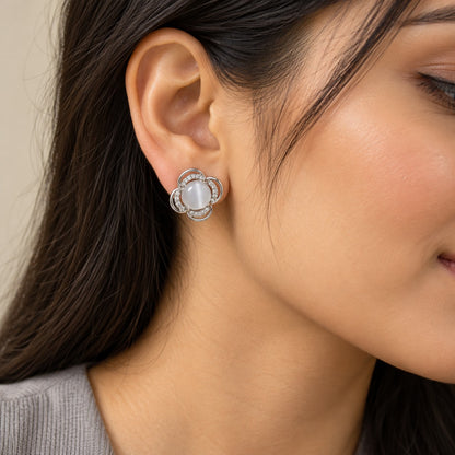 Woman wearing a silver flower cat eye stone stud earring, close-up of ear and jawline