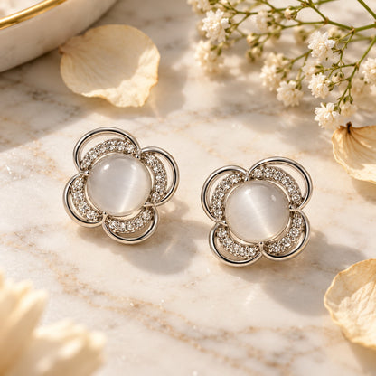 Silver flower cat eye stone stud earrings on white marble with soft dried petals