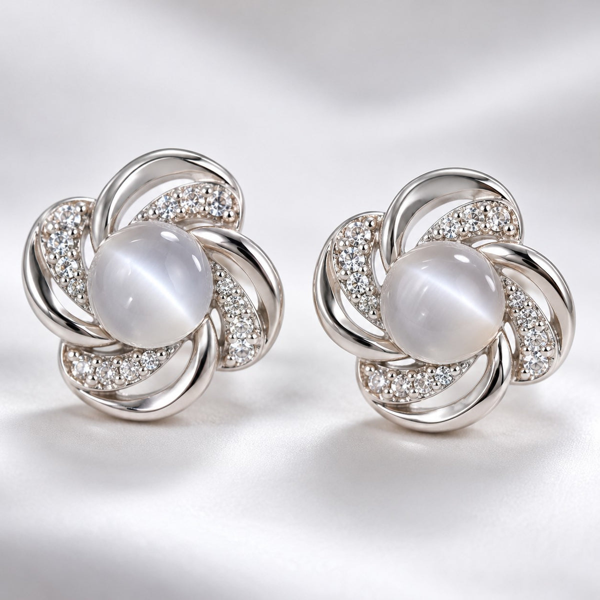 Close-up of the milky cat eye stone and crystal swirl petals on a silver stud earring
