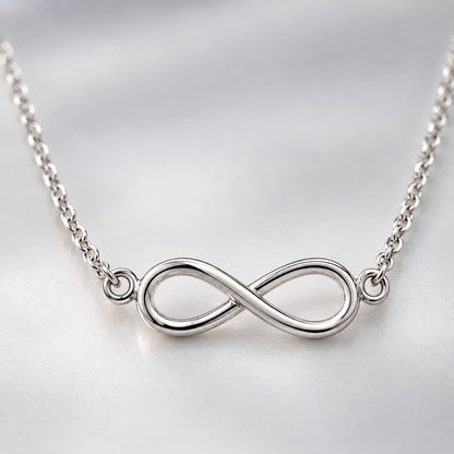 Macro view of the silver infinity pendant and fine twisted chain links