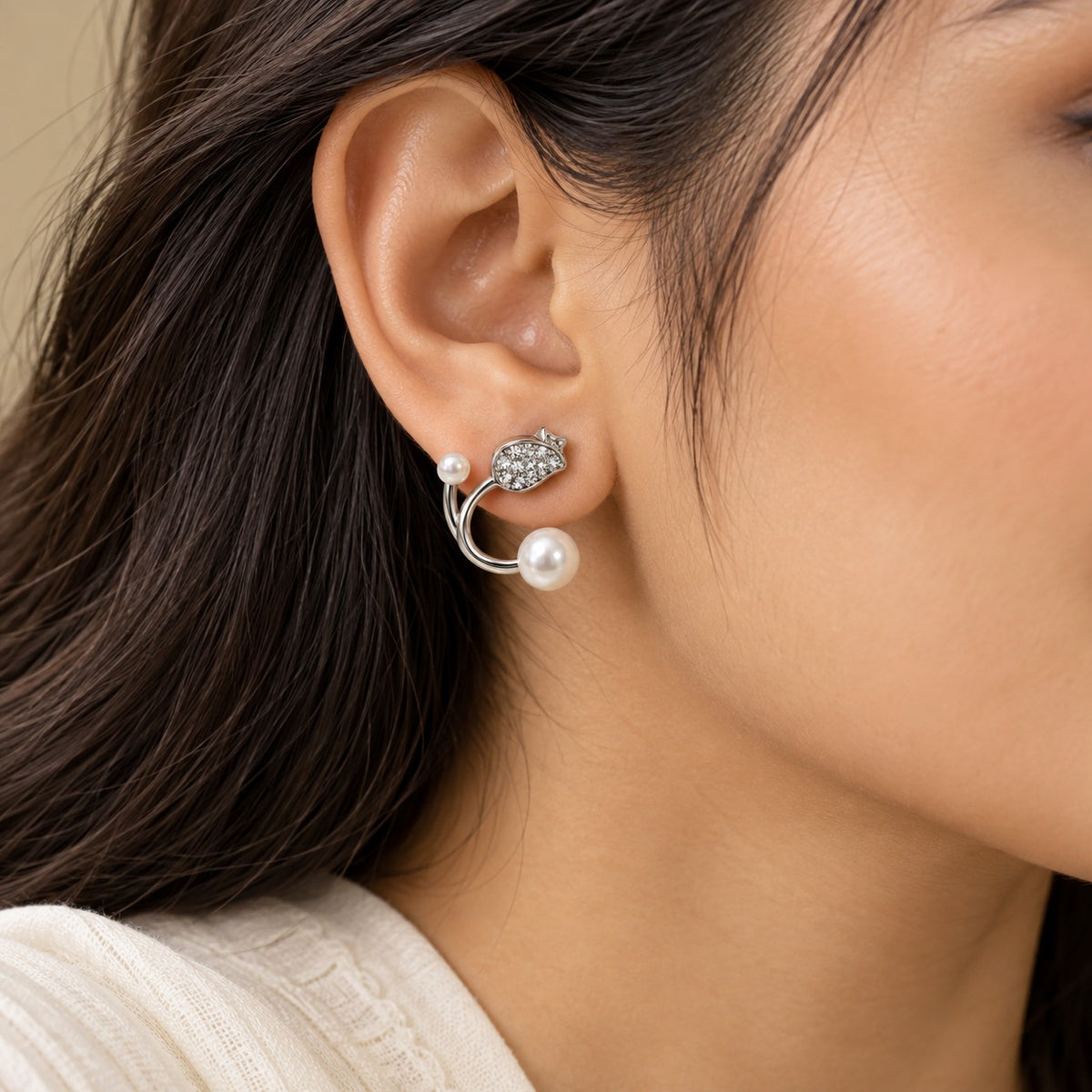 Woman wearing silver pearl open hoop stud earrings, close-up of ear and jawline
