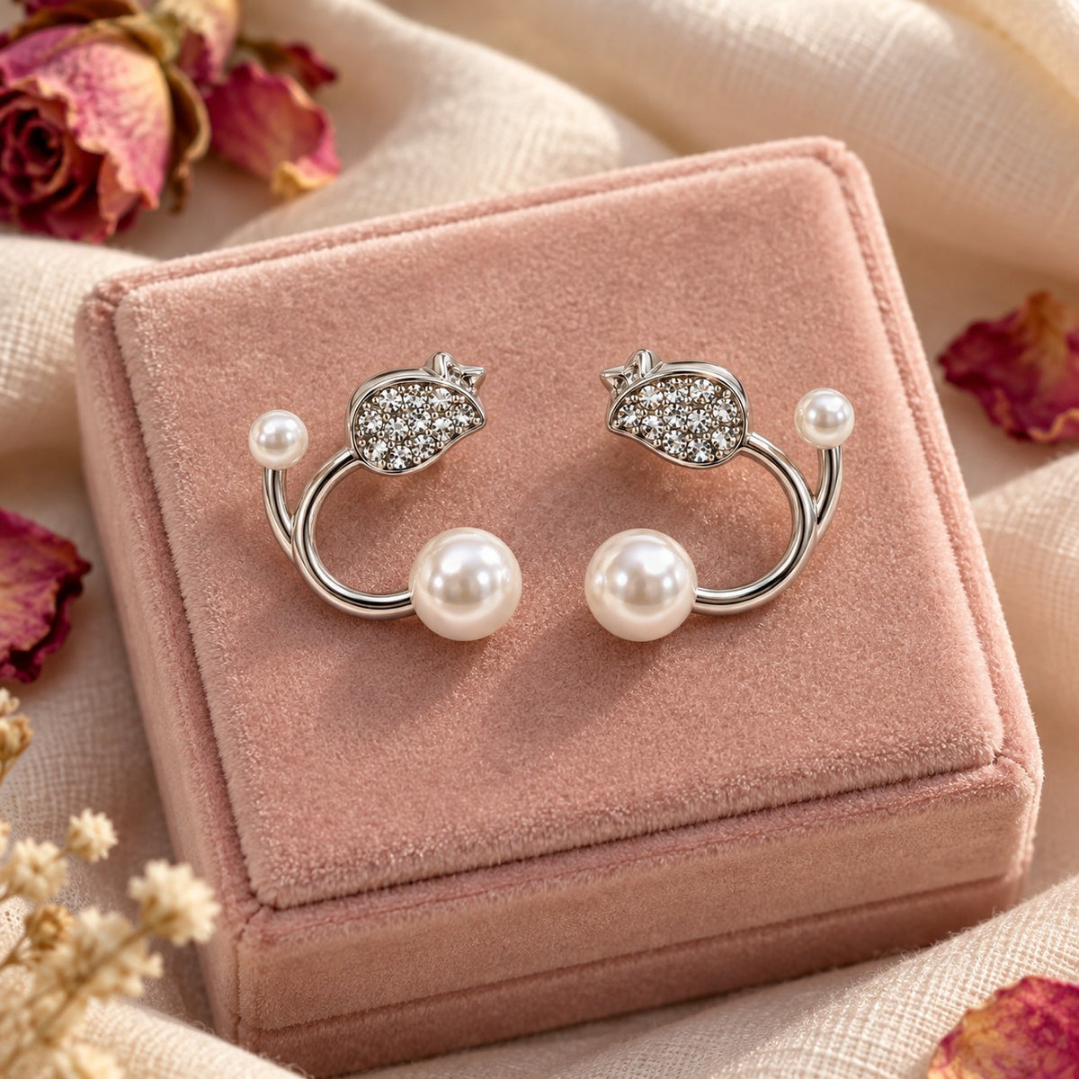 Silver pearl open hoop stud earrings on a blush velvet jewellery box with dried petals