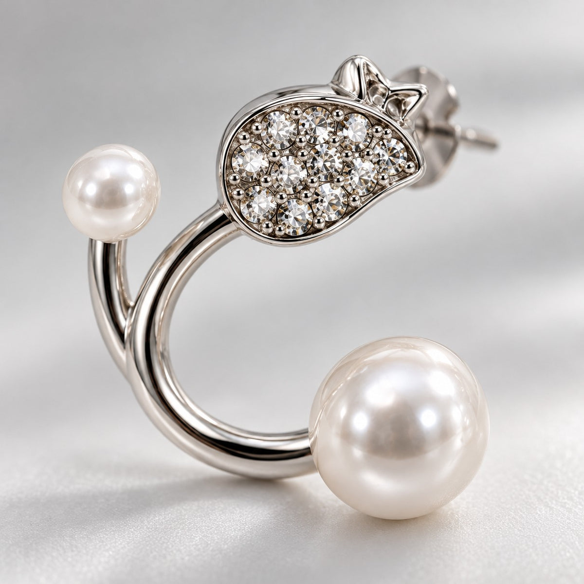 Close-up of the crystal-paved leaf and faux pearls on a silver open hoop stud earring