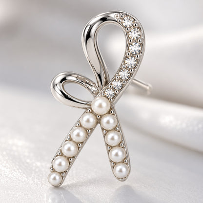 Close-up of crystal-lined loop and faux pearl tails on a silver ribbon bow earring