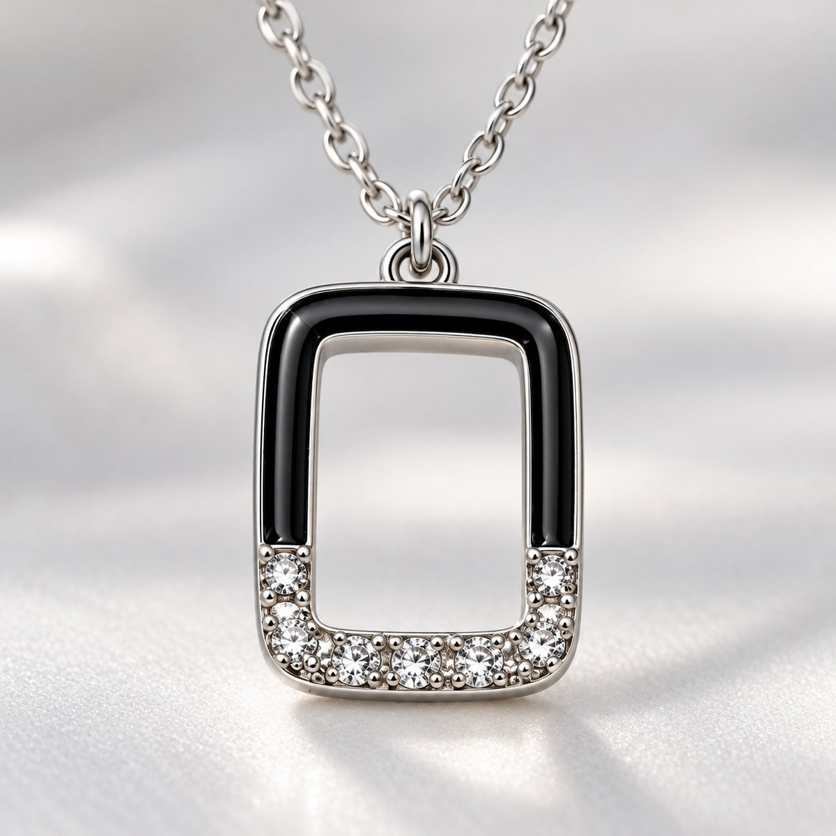 Close-up of the crystal-set base and black enamel edges of the silver rectangle pendant