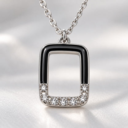 Close-up of the crystal-set base and black enamel edges of the silver rectangle pendant