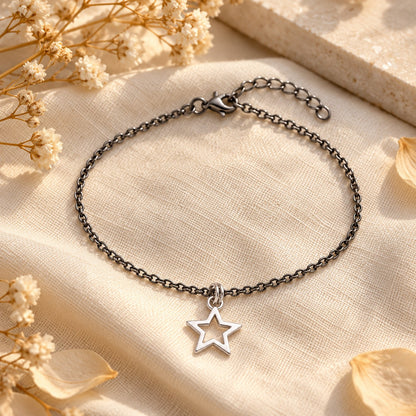 Silver star charm bracelet styled on linen with dried flowers in warm light