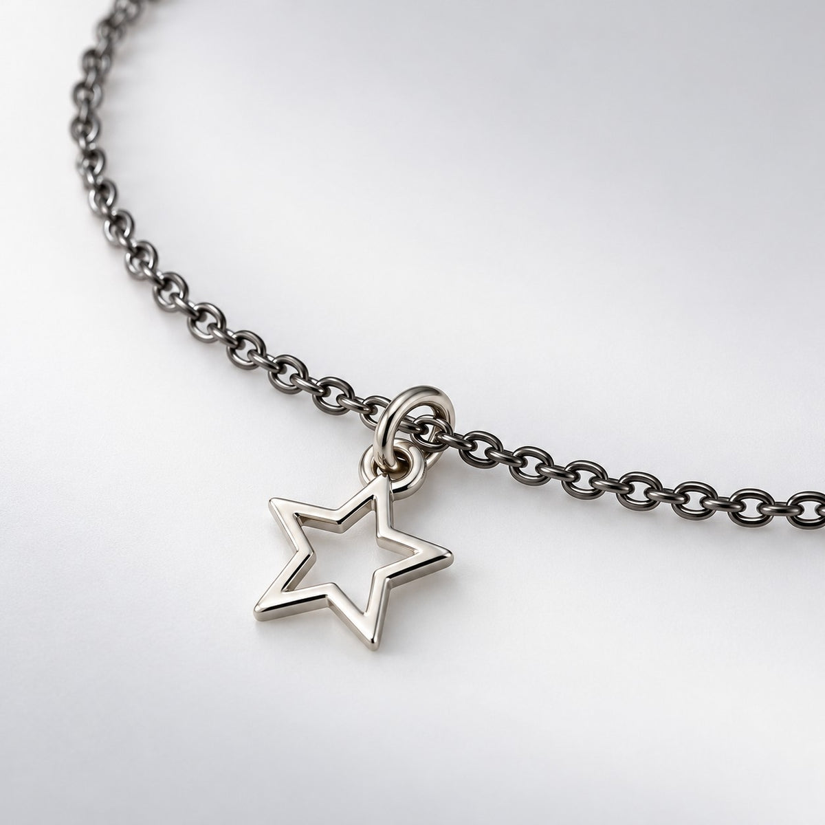 Close-up of the open silver star charm and fine dark chain of the star charm bracelet