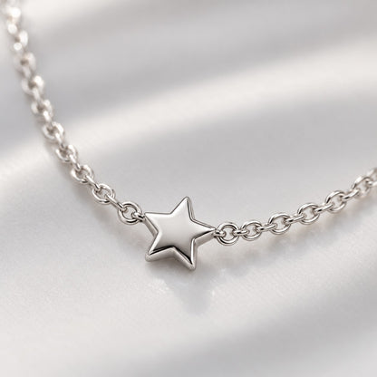 Close-up of the tiny five-point star on the silver chain necklace