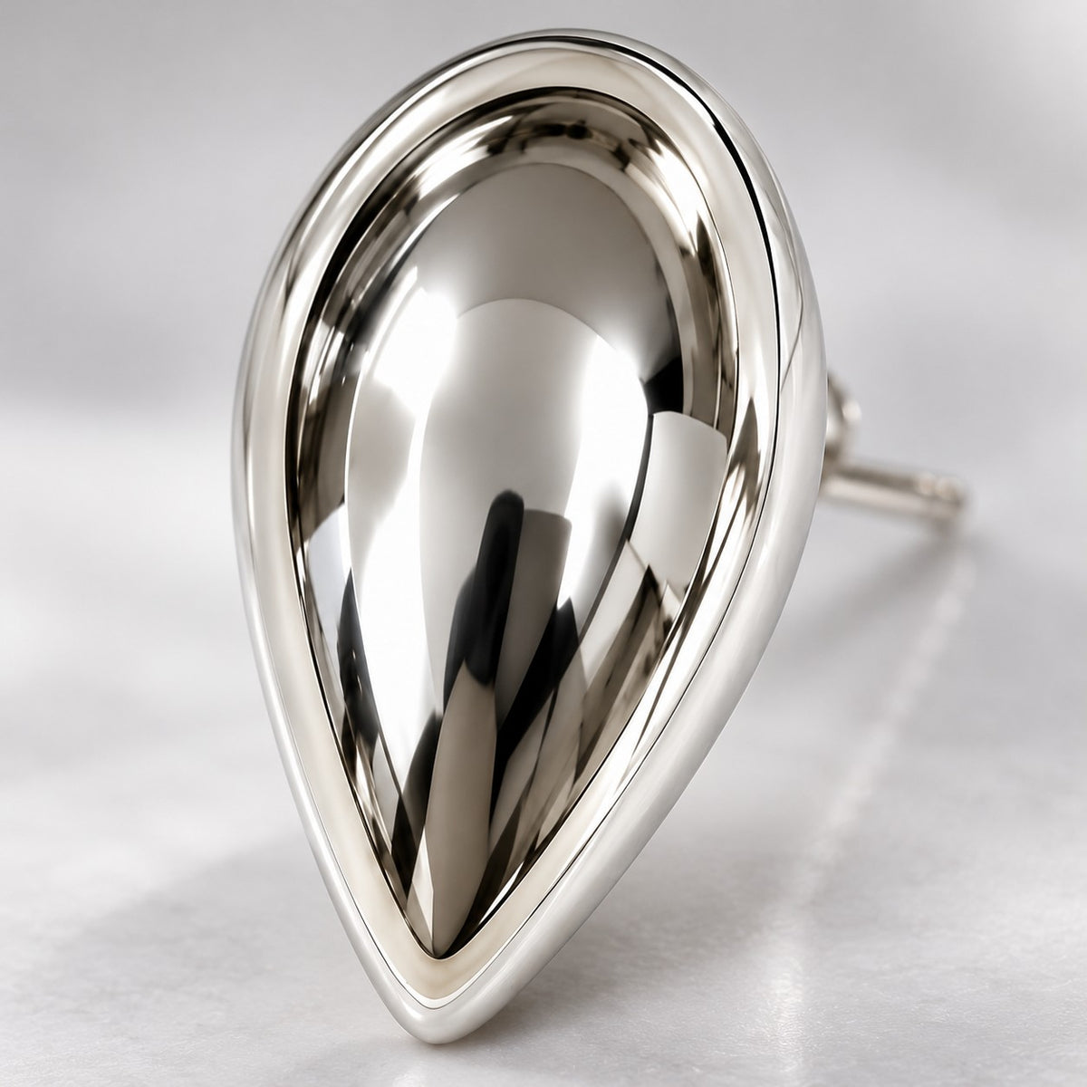 Macro view of the polished curve of a silver teardrop dome stud earring